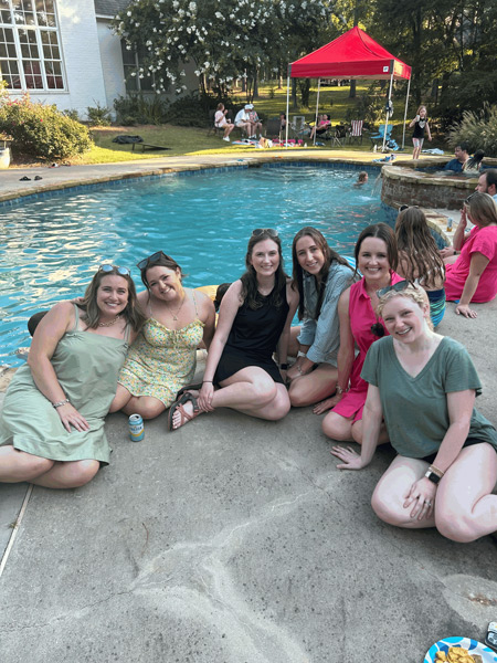 six residents sitting by a swimming pool